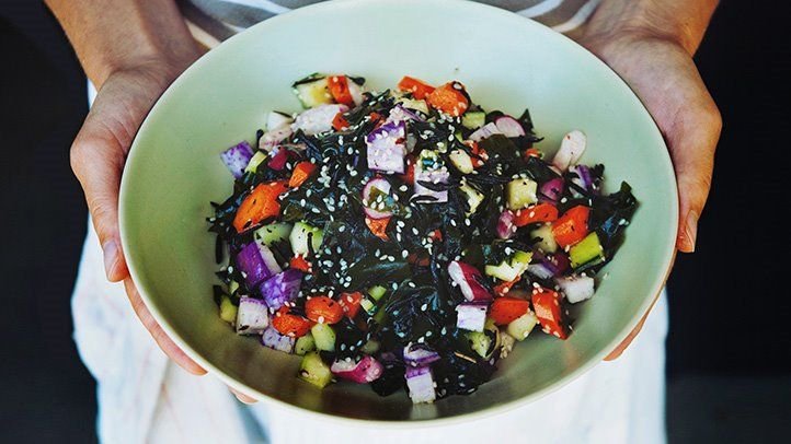 A plate of thyroid-supportive foods including fish, nuts, seeds and leafy greens