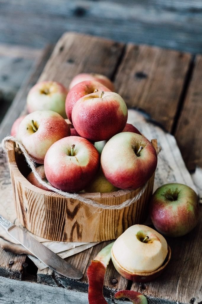 A wooden crate of red apples on weathered boards, one apple cut in half