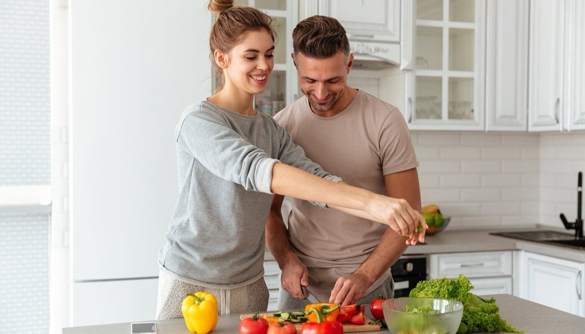 A couple preparing a vegetable salad together in a kitchen